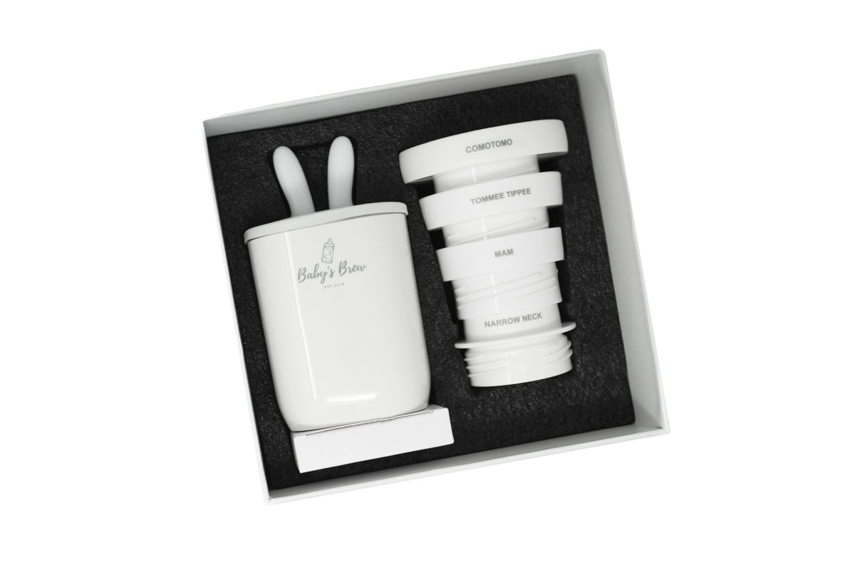 Baby's Brew portable bottle warmer and four bottle adapters arranged in an open box by Mama's Dream