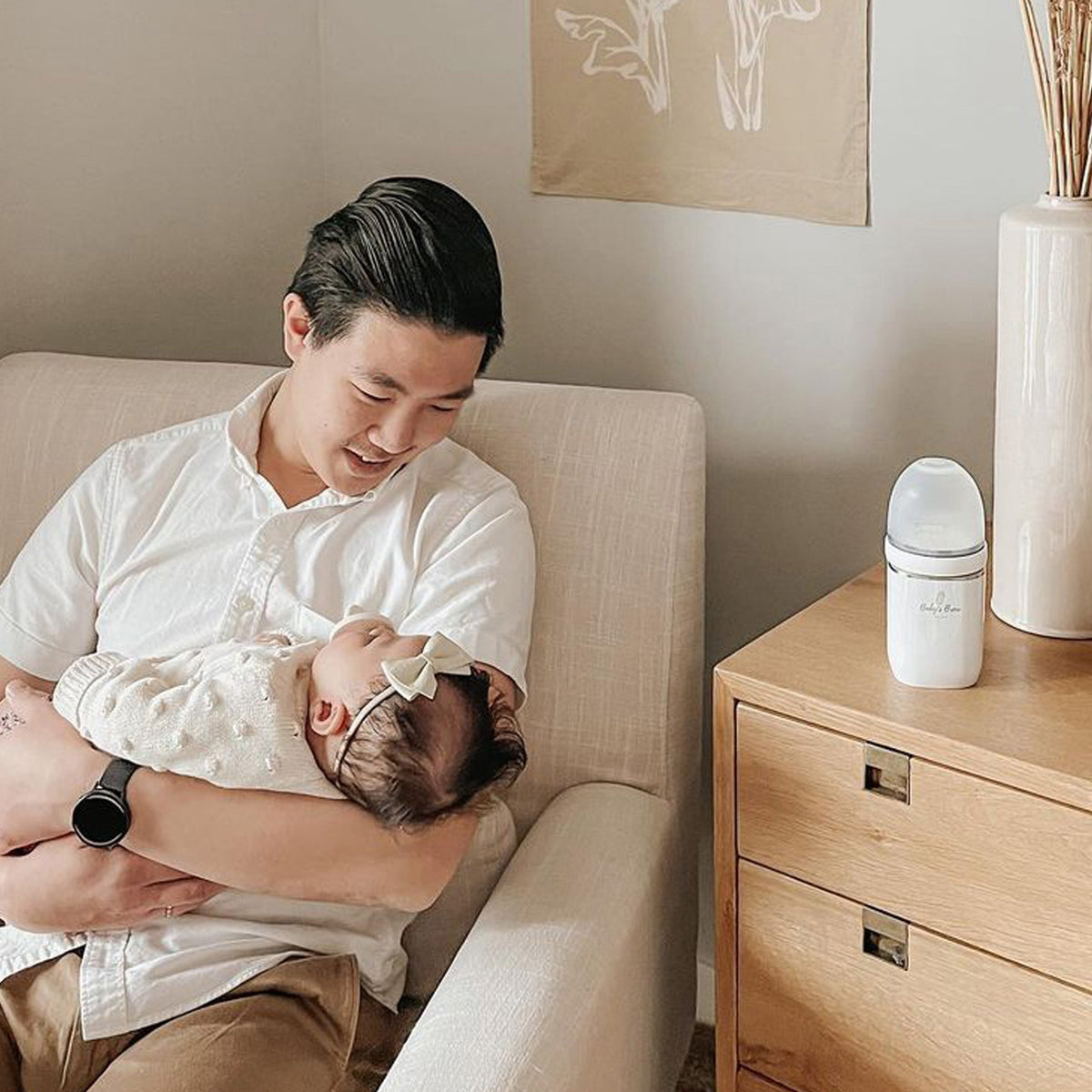 Father holding his baby beside a Baby's Brew portable bottle warmer by Mama's Dream