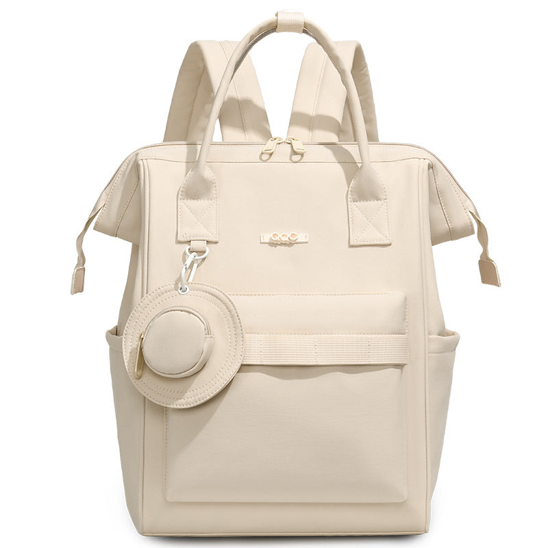Beige convertible diaper bag backpack with top handles, side pockets and front storage compartment by Mama's Dream