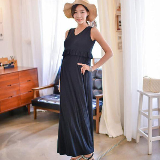 Pregnant woman wearing a black sleeveless maternity nursing maxi dress with discreet layered breastfeeding access by Mama's Dream