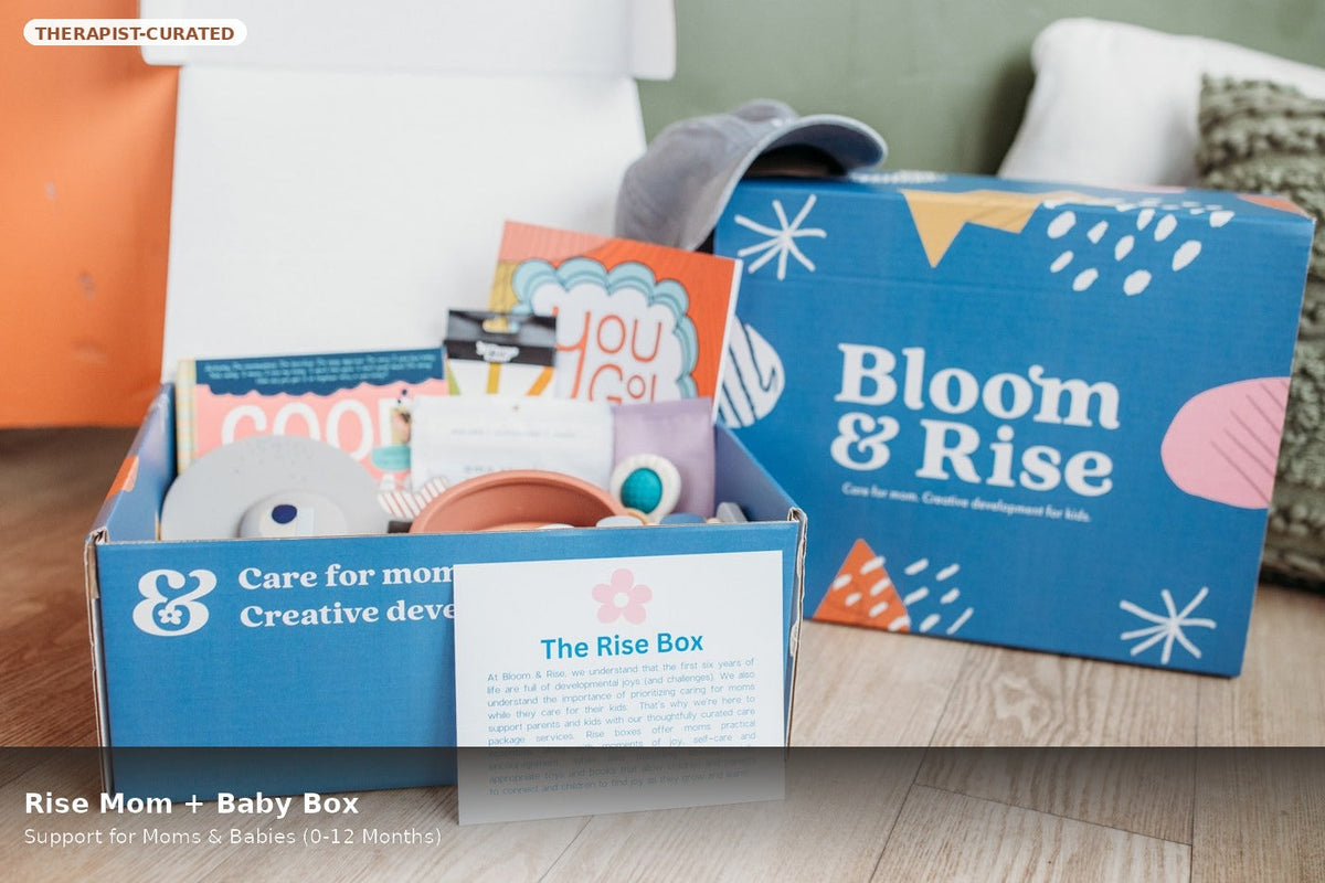 Open Bloom & Rise Mom and Baby Box with books, baby items and a welcome card by Mama's Dream
