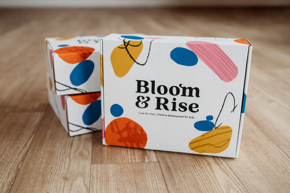 Bloom & Rise postpartum care box with colorful packaging on a wooden floor by Mama's Dream
