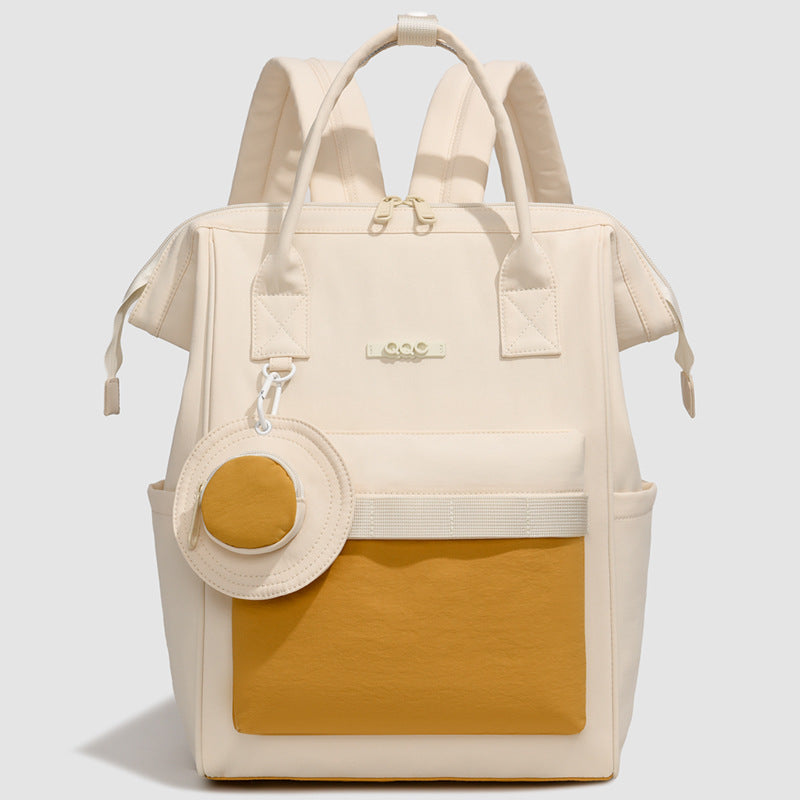 Cream convertible diaper bag backpack with mustard front pocket, top handles and side pockets by Mama's Dream