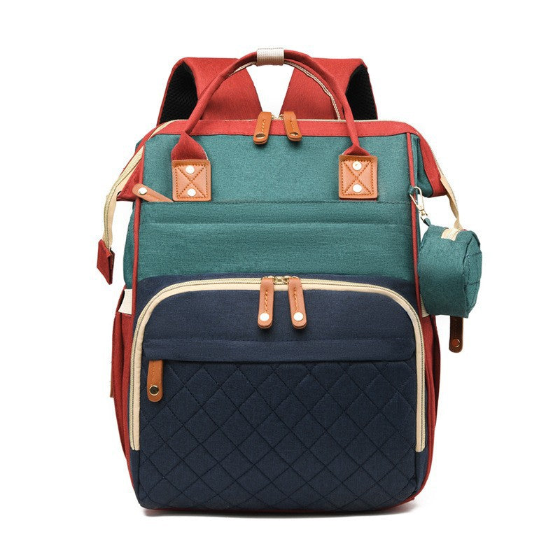 Multicolor quilted diaper bag backpack with red, teal and navy panels, top handles and side accessory pouch by Mama's Dream