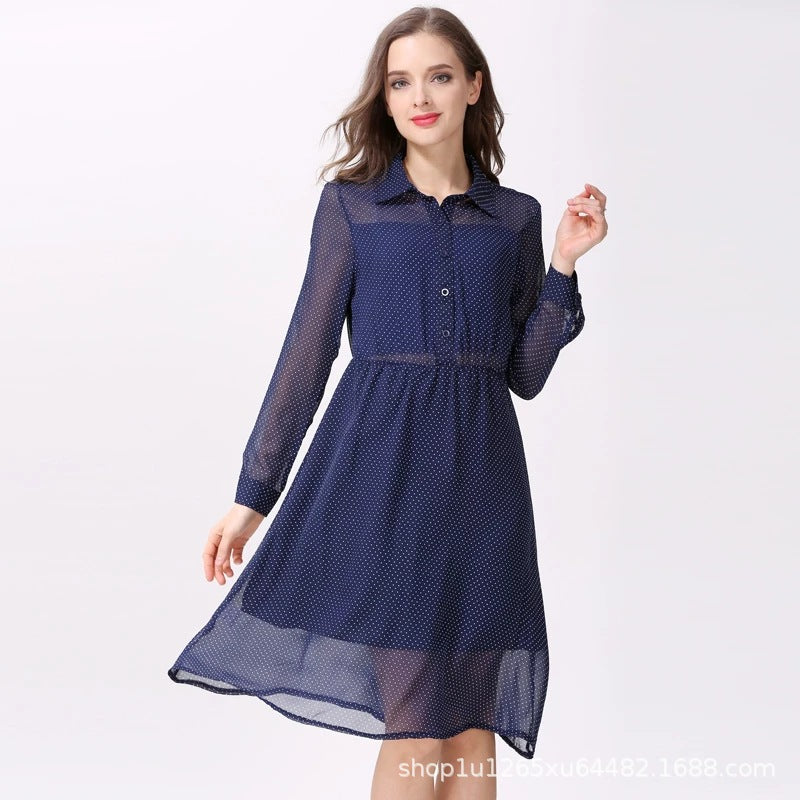 Front view of a woman wearing a navy polka dot maternity nursing dress with sheer sleeves and a flowy hem by Mama's Dream