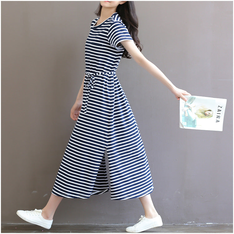 Woman walking in a navy and white striped maternity midi dress with a waist tie and side slit by Mama's Dream