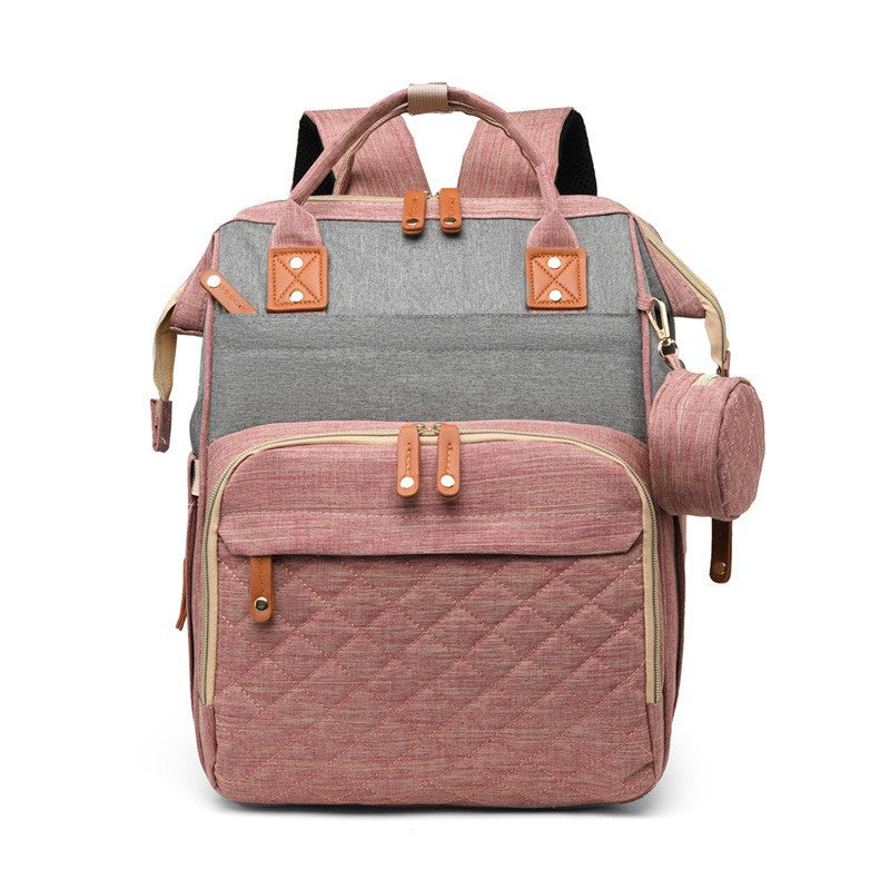 Pink and gray diaper bag backpack with quilted front pocket, top handles and side accessory pouch by Mama's Dream