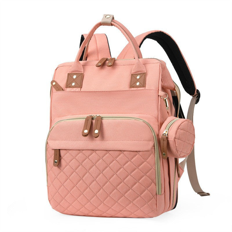Pink quilted diaper bag backpack with top handles, padded shoulder straps and side accessory pouch by Mama's Dream